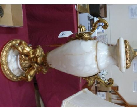 A fine alabaster and bronze ormolu table lamp, with mounts cast as scrolled animal masks, the base as three putti, one with a