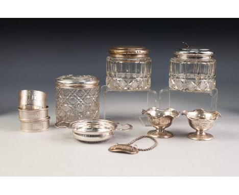 THREE CYLINDRICAL CUT GLASS DRESSING TABLE JARS WITH PULL-OFF SILVER COVERS, together with THREE ENGINE TURNED SILVER NAPKIN 