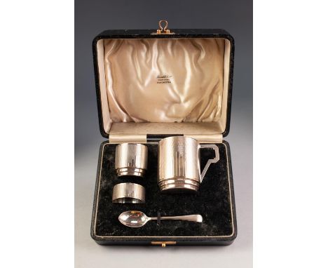 EDWARD VIII CHILDâ€™S ART DECO FOUR PIECE ENGINE SILVER CHRISTENING SET IN CASE, comprising: MUG, EGG CUP AND SPOON, and NAPK