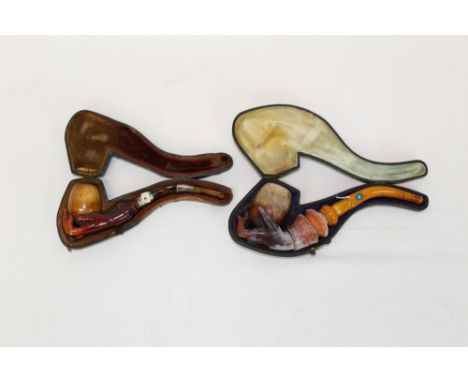 Two late 19th century meerschaum pipes carved in the form of a hand holding the pipe bowl, with amber mouthpieces, 16cm - 20c