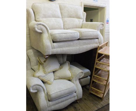 A modern beige upholstered two piece suite comprising a two seater sofa and armchair and a matching foot stool