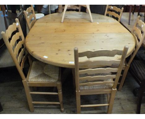 A modern Pine extending dining table on column support and six Beechwood ladder back dining chairs