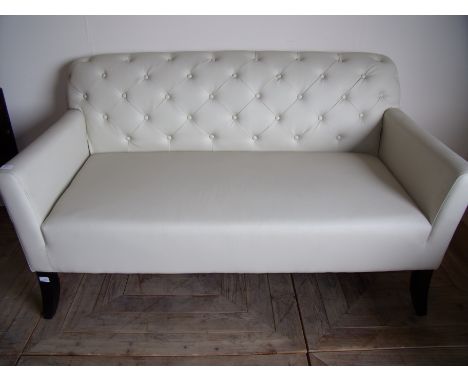 As new cream leather effect two seat sofa with deep button back on ebonised supports (width 147cm)