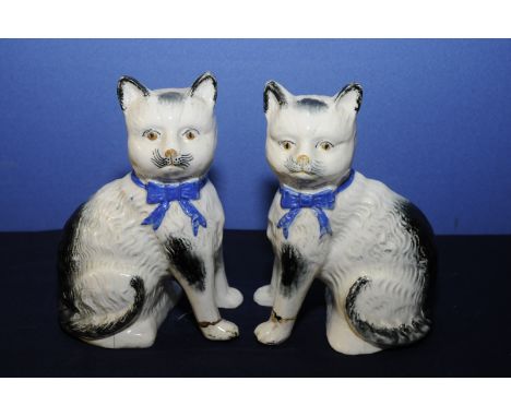 Pair of 18th C English ceramic seated cats with free standing front paws and blue neck bows (22cm high) (a/f)