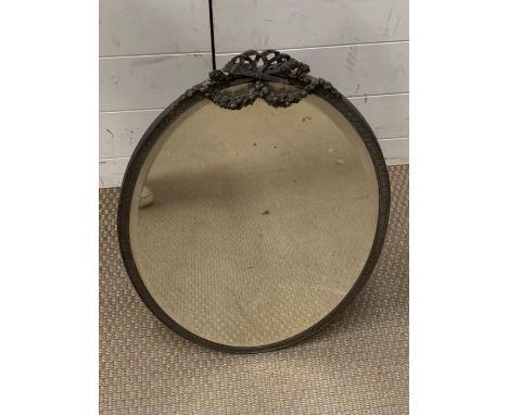 An oval mirror with ribbon top on table top stand 