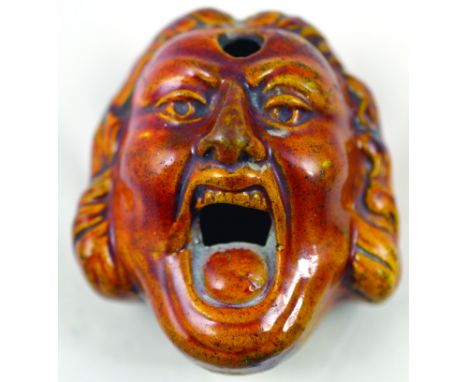 BELLOWING MAN INKWELL. 3ins long, variating brown &amp; tan glaze in shape of bewigged mans face with gaping mouth. Ink apert