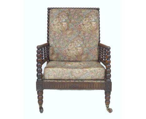 An early Victorian oak bobbin turned armchair, with loose upholstered seat and back cushions, raised upon castors, 61 by 80 b