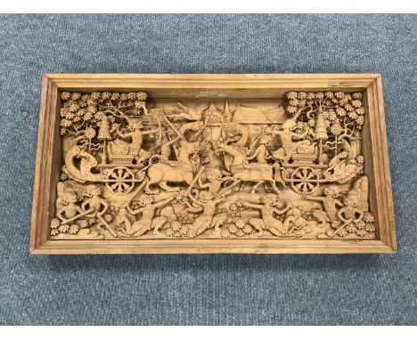 An early 20th century carved Eastern panel, profusely carved with figures in battle, 118 cm x  61 cm. 