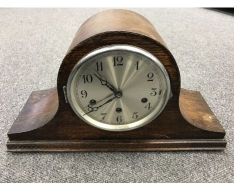 An oak cased mantel clock with silvered dial  CONDITION REPORT: The pendulum is present but no key. The clock ticks away when