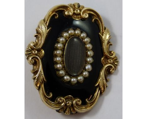 A Victorian gold, black enamel and half pearl mourning brooch, of oval design, the woven hair panel with pearl border, scroll