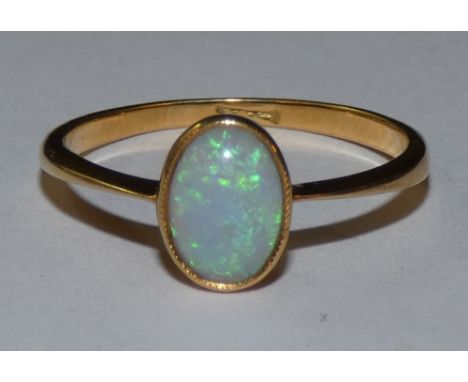 An 18ct gold opal single stone ring, milligrain collet set with a cabochon stone, size O.