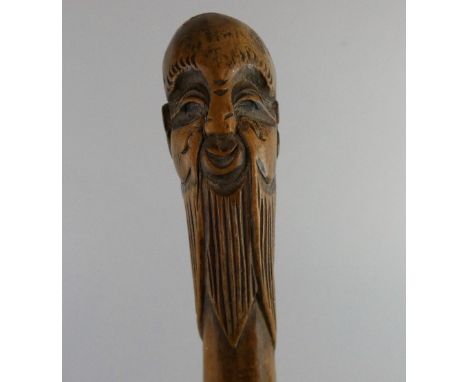 An Oriental carved walking stick, the terminal with a long bearded gentleman.