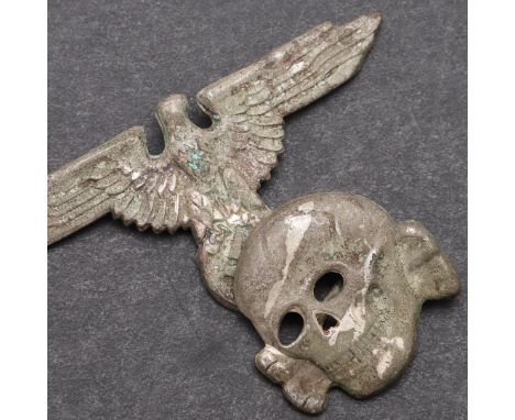 A SECOND WORLD WAR GERMAN SS PEAKED CAP INSIGNIA SET. An insignia set comprising zinc eagle with wide wings with RZM and make