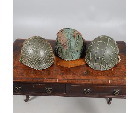 THREE AMERICAN STEEL HELMETS AND LINERS. Three similar American post Second World War steel helmets, each with liner and chin