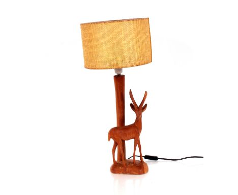 A carved hardwood antelope decorated table lamp with wicker type cylindrical shade 