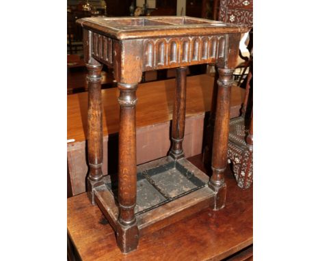 An oak two-division stick-stand with a drip-tray in the fold of a joint stool 