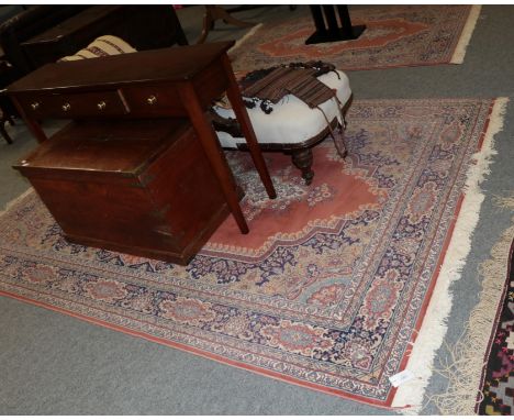 A machine made carpet the field with central medallion framed by indigo borders, 397cm by 297cm, together with a similar rug 