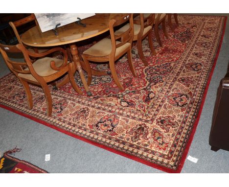 A machine made carpet of Oriental design, the terracotta field with central medallion framed by cream borders, 406cm by 300cm