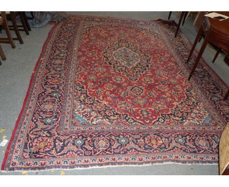 A Kashan carpet, Central Iran, circa 1960, The raspberry field of vines around a medallion framed by spandrels and indigo bor