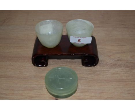 Two Chinese jade Mijiu cups and lidded trinket box with hardwood stand
