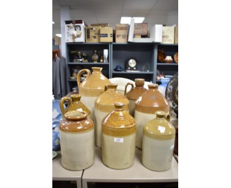 Seven vintage flagons and a stoneware jar, one of interest to S.H Cowell wine and spirit merchant, Ipswich 33cm, wear and gla