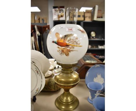 A 20th century brass oil lamp, with glass chimney and mid century opaque shade with pheasants in flight.