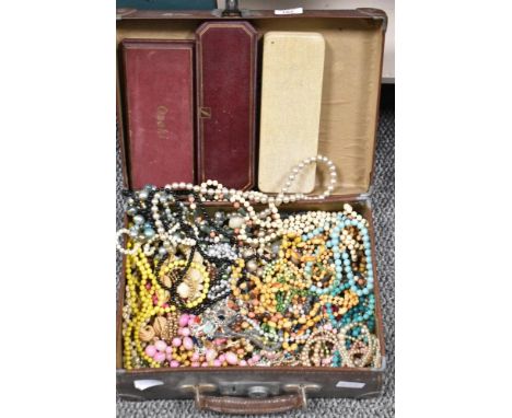 A vintage suitcase containing an assortment of vintage beaded costume jewellery, including Simulated pearls.