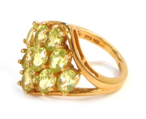 A chunky dress ring, of diamond shape set with nine oval peridots, yellow metal stamped 14k, size M, 6.5g all in.