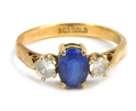 A dress ring, set with three paste stones, central blue stone flanked by two white stones, in claw setting on a yellow metal 