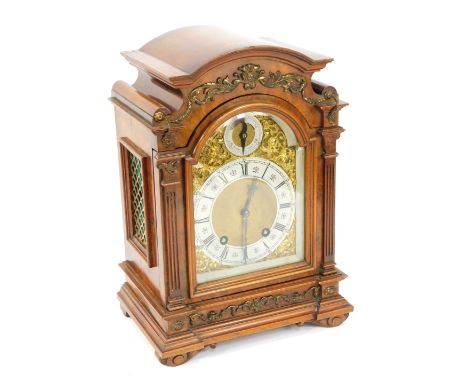 A late 19thC walnut cased mantel clock, with an arched top with brass foliate scroll casting, brass break arch dial with gilt