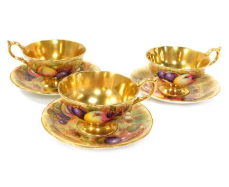 A set of three Aynsley Orchard Gold pattern tea cups and saucers, each painted with fruit by N Brunt,with a gold lustre inter