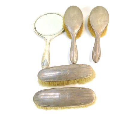 A George V silver backed dressing table set, with engine turned decoration, circular vacant reserve, comprising a hand mirror