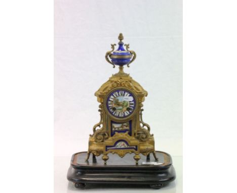 French Gilt key wind metal mantle clock with painted Enamel dial, panel and finial and a vintage Wooden stand
