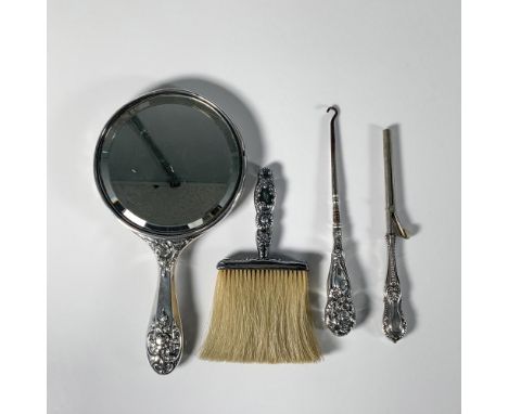 A collection of opulent personal care items, including a sterling silver hand mirror, a button hook with a sterling silver ha