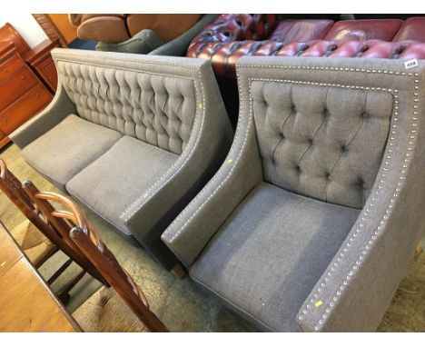 A grey button back and chrome studded settee and matching armchair