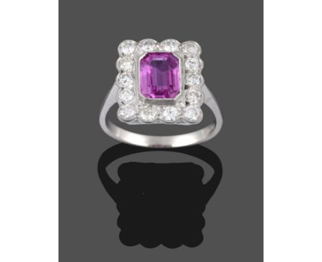 A Pink Sapphire and Diamond Cluster Ring, the emerald-cut pink sapphire within a border of round brilliant cut diamonds in wh