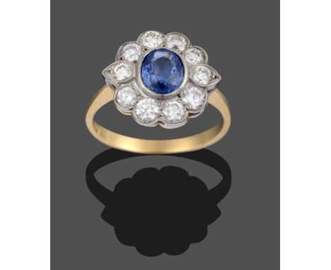 A Sapphire and Diamond Cluster Ring, an oval cut sapphire within a border of round brilliant cut diamonds in white millegrain