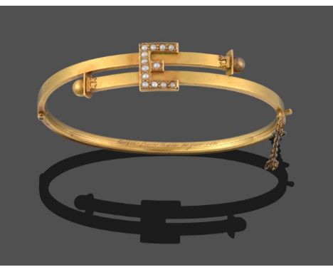 A Seed Pearl Bangle, formed of two cross over bars terminating to yellow beads, with a central initial 'E' set with seed pear