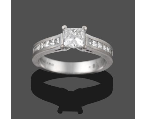 An 18 Carat White Gold Diamond Solitaire Ring, the princess cut diamond in a claw setting, to shoulders channel set with prin