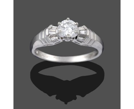 A Platinum Diamond Solitaire Ring, a round brilliant cut diamond in a claw setting, to tapered baguette cut diamond angular t