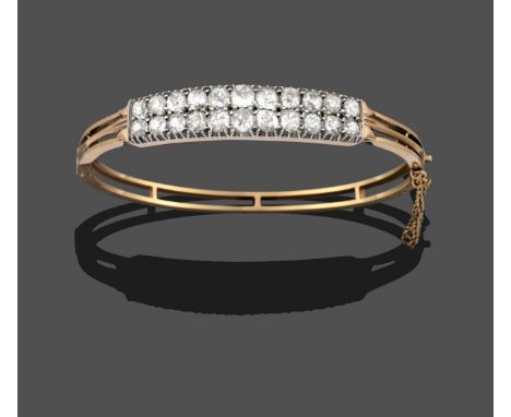 A Diamond Bangle, two rows of graduated old cut diamonds in white claw settings, to a yellow hinged double row plain polished
