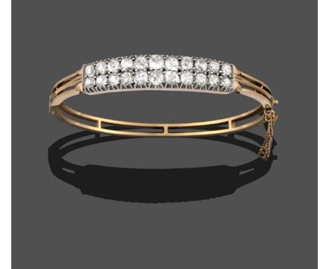 A Diamond Bangle, two rows of graduated old cut diamonds in white claw settings, to a yellow hinged double row plain polished