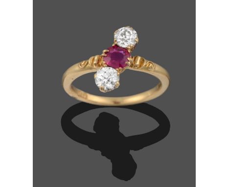 A Ruby and Diamond Three Stone Ring, a round cut ruby flanked by two old cut diamonds in yellow scroll settings, positioned v