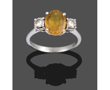 An 18 Carat White Gold Yellow Sapphire and Diamond Three Stone Ring, the oval cut yellow sapphire sits between two round bril