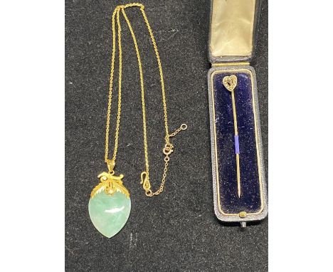 A yellow metal chain and jade pendant, along with a yellow metal stick pin. 