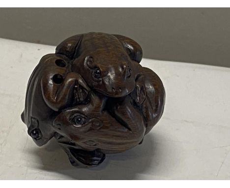 A hardwood netsuke depicting frogs on a ball. Signed. 