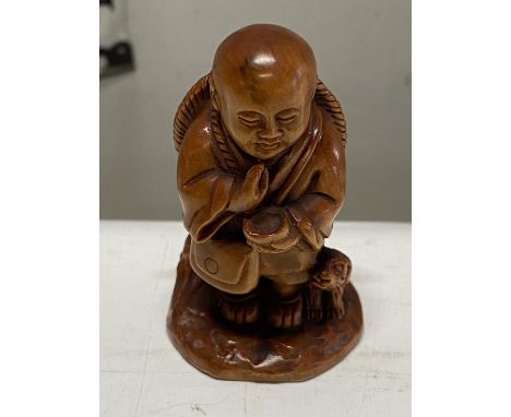 A boxwood netsuke depicting a boy and dog. Signed to base. 