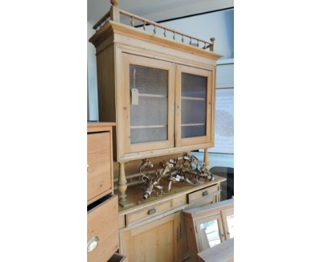A 19th Century East European pine buffet, upper section enclosed by two glazed doors over frieze drawers and panelled covered