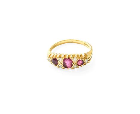 An 18 Carat Gold Ruby and Diamond Ring, the central oval cut ruby flanked by pairs of round brilliant cut diamonds, with a fu