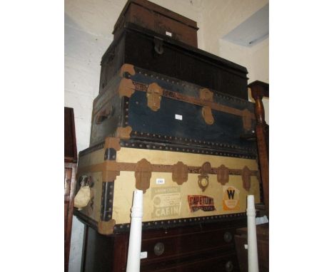 Large cream covered cabin trunk, another blue covered cabin trunk, black painted car trunk and a black painted safety deposit